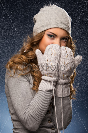 Cute curly girl wearing mittens during snowfall