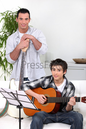 Мужчина учит подростка играть на гитаре