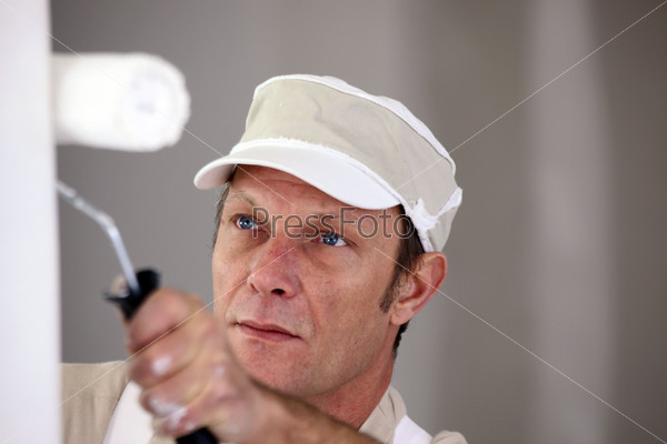 Man using paint roller on wall