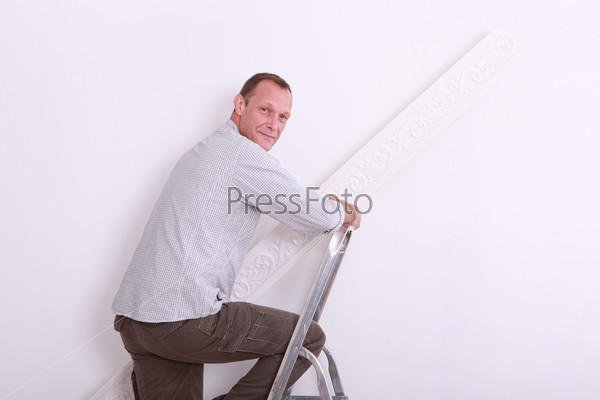 Man with step-ladder holding roll of wallpaper