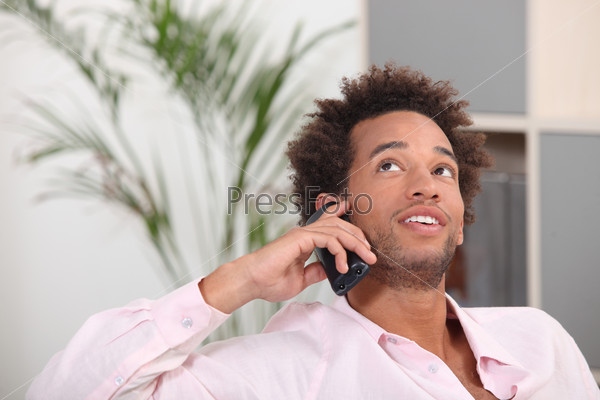 young Afro-American talking on his cell at home