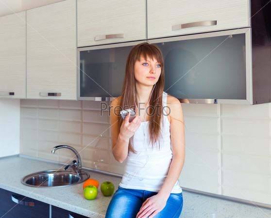 Young girl in the kitchen listening to music on headphones