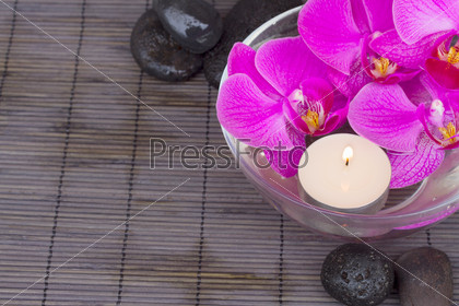 bowl with orchids and candle and massage black  stones