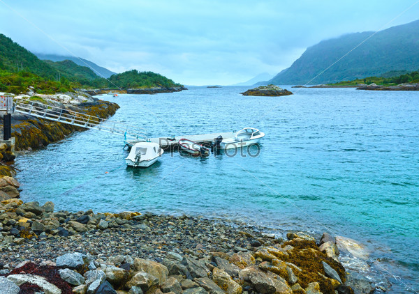 Norwegian Sea cloudy morning view with stony coast and motorboats (not far Vagan, Norway).