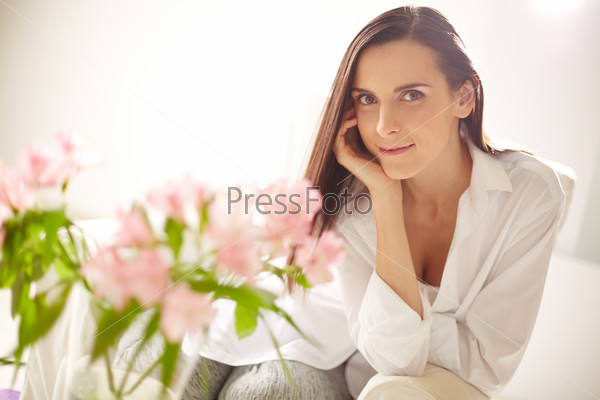 Portrait of lovely lady looking at camera with bunch of pink flowers in front