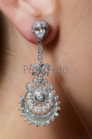 Female ear in jewelry earrings close up