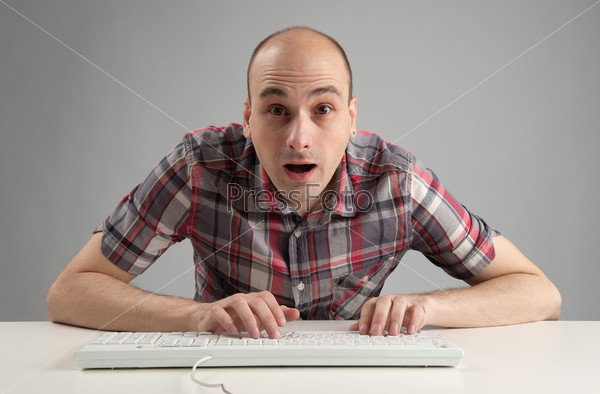 handsome shocked man working on computer and looking at camera