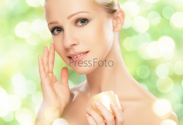 beauty young woman with cream and a natural skin care in herbal green background