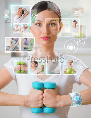 Woman doing exercise with dumbbells wearing smart wearable device with futuristic interface