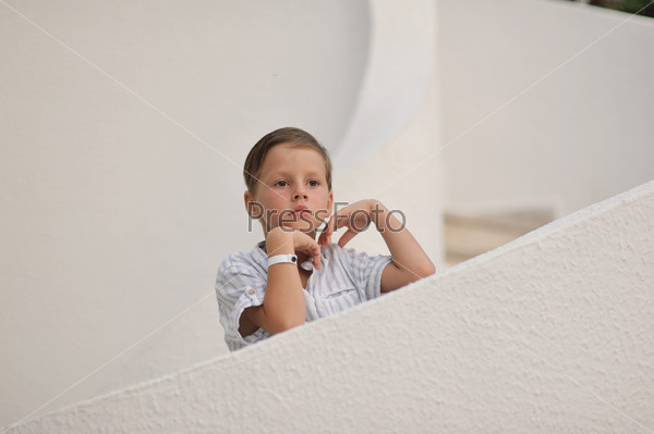 cute little boy in white shirt standing on white stairs