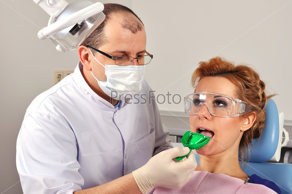 Girl in dentist chair with dental impression tray in her mouth, stock photo