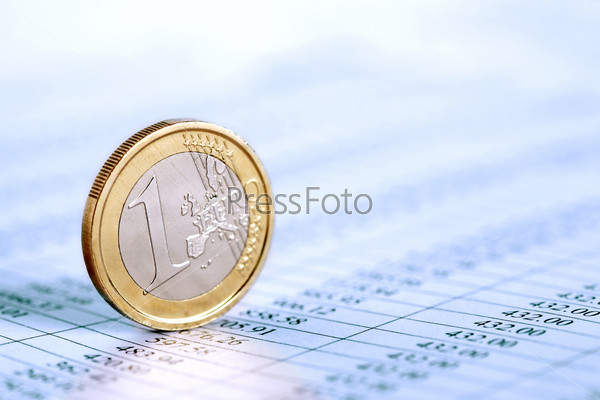 One Euro coin standing on paper background with digits table