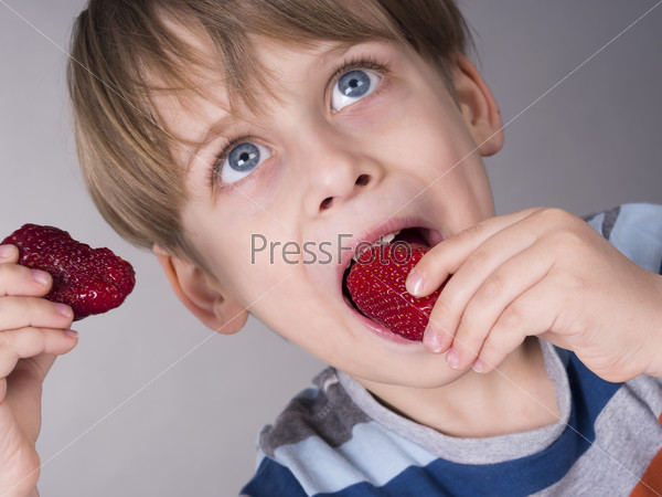 Мальчик ест клубнику