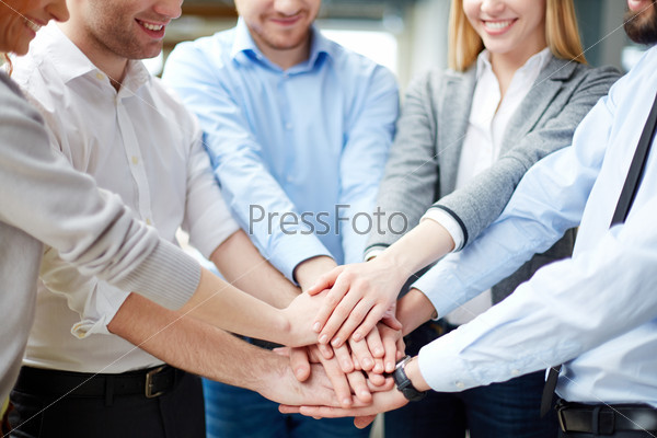 Arms of business partners keeping their hands on top of each other symbolizing teamwork
