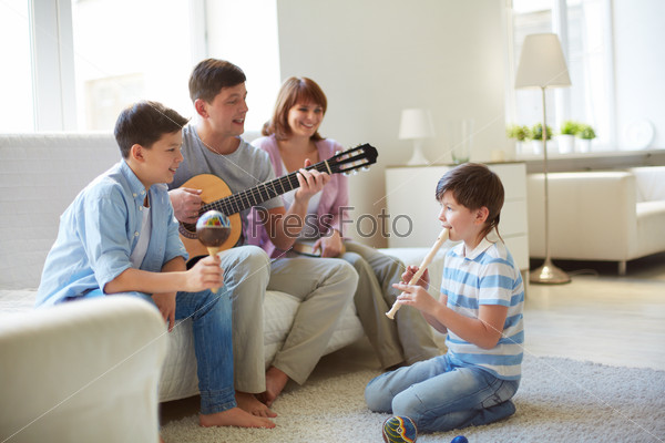 Portrait of handsome siblings and their father playing musical instruments at home