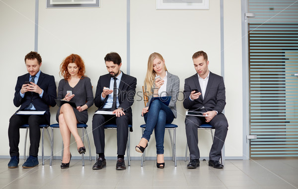 Row of several business partners using their mobile phones