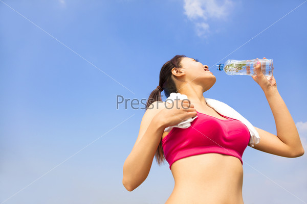 sporty woman drinking water bottle after jogging or running