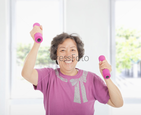 Happy senior woman working out with dumbbells