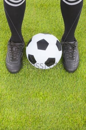 Soccer player\'s feet and football on field