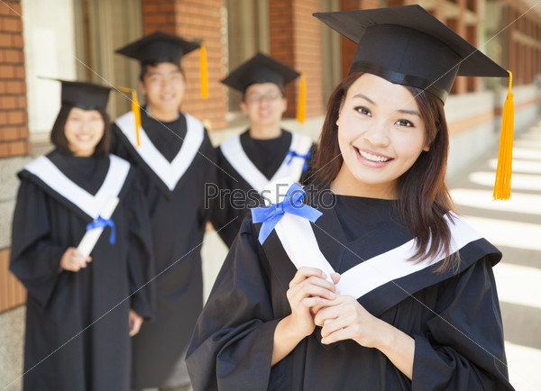 smiling college graduate holding diploma with classmates