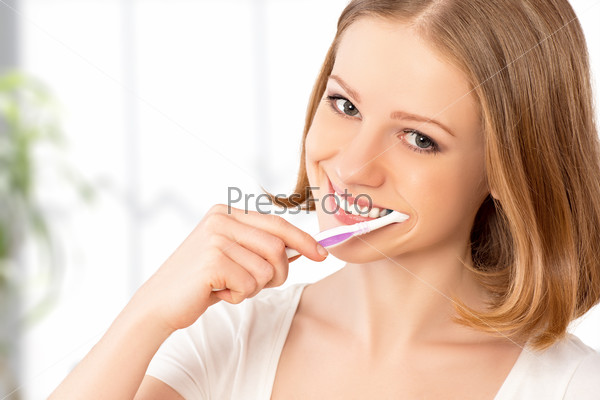 Healthy happy young woman with snow-white smile brushing her teeth with a toothbrush
