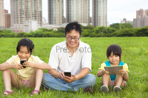 happy family using smart phone and tablet pc outdoor