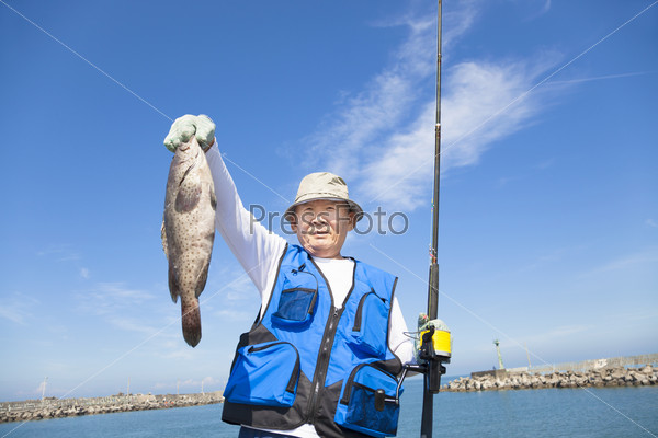 happy senior fisherman showing large grouper