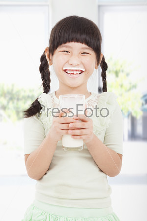 Happy little girl holding a glass of fresh milk