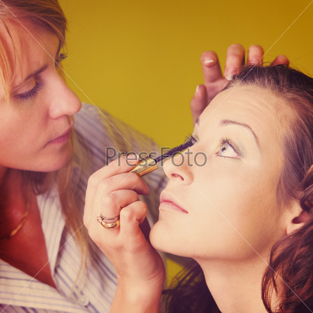 makeup artist is applying cosmetics on model face