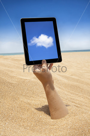 hand holding touch screen computer on the beach