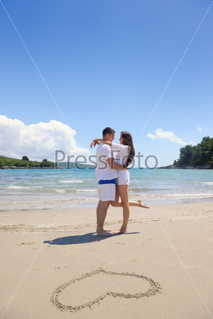 happy couple have fun on the beach with heart on sand