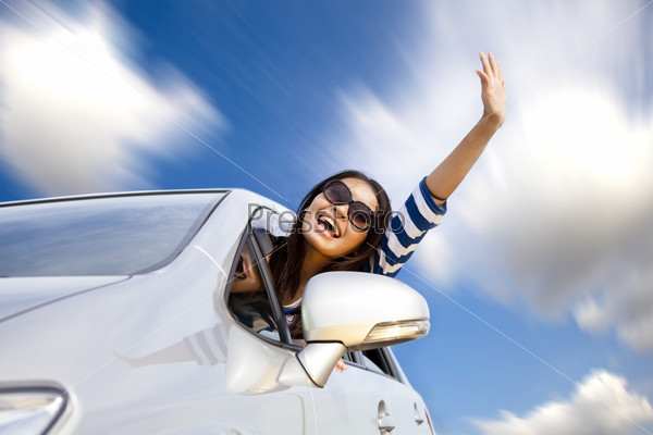 Happy young woman in car driving on the road