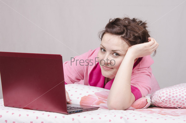 Happy girl in bed works for laptop