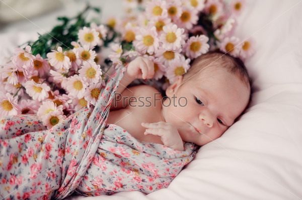 little baby wrapped in a blanket color and bouquet of flowers
