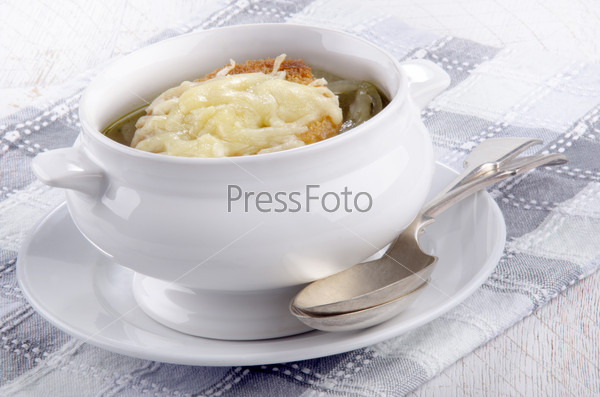 french onion soup in a white bowl with toasted bread and grated cheese