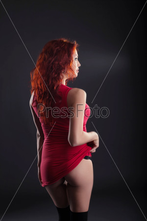 Sexy red-haired woman posing back to camera