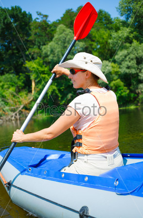 Happy woman paddling a kayak on the river, enjoying a lovely summer day