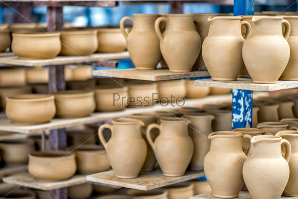 Shelves with ceramic dishware in pottery workshop, stock photo