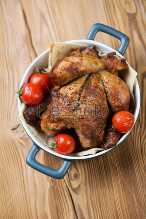 Whole baked chicken with tomatoes, vertical shot, above view