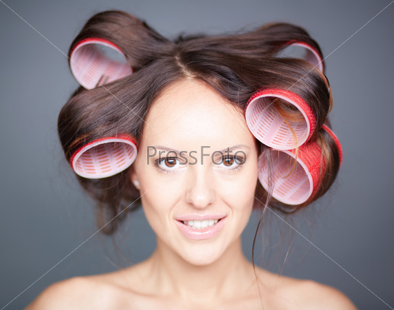 Close-up of happy woman with big hair-rollers looking at camera