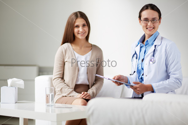 Female psychiatrist looking at camera with her patient near by