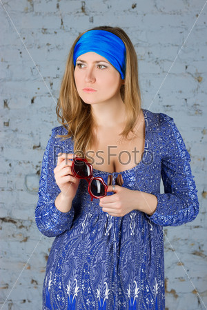 Girl in a blue scarf on her head against the wall