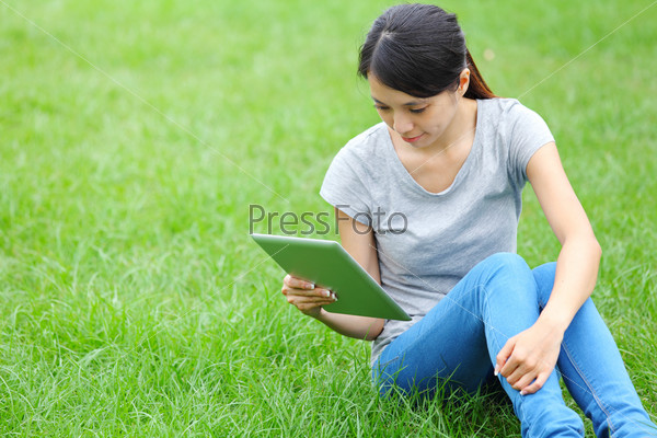 Женщина с планшетом сидит на траве