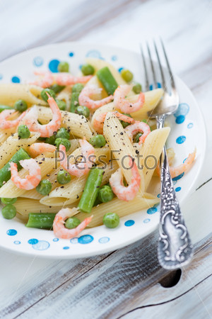 Penne pasta with boiled shrimps and vegetables, close-up