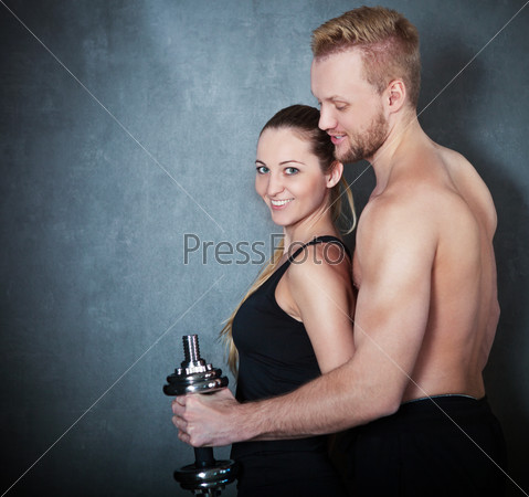 Athletic couple with a dumbells near the wall