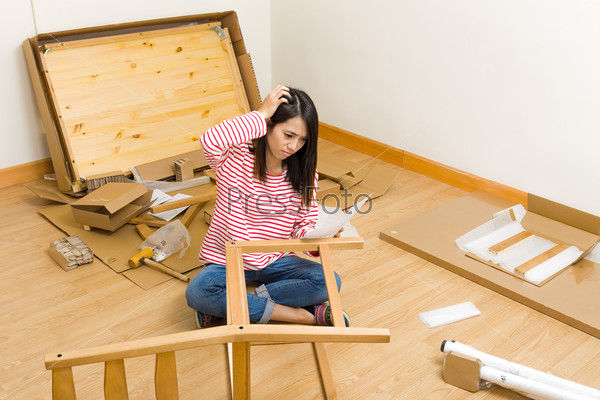 Asian woman assembling new chair with instruction
