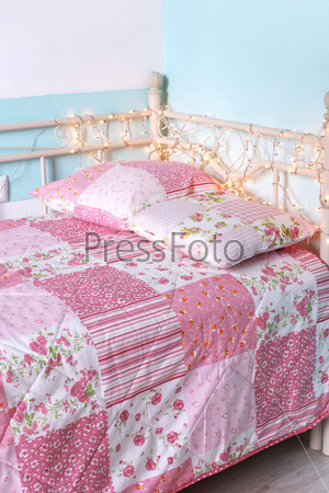 Photo of girl\'s bed with pattern bedding on it