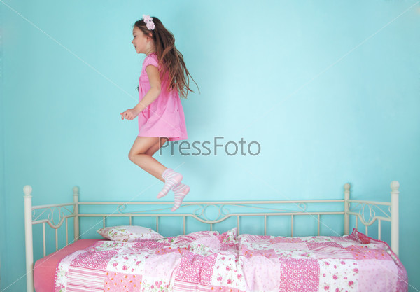 8 years old girl jumping on the bed at home