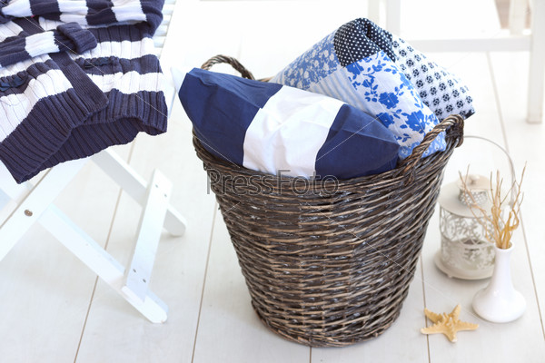 Wicker clothes basket with patchwork quilt and a pillow inside