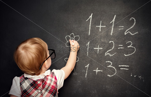 baby girl pupil draws a chalk on a blackboard